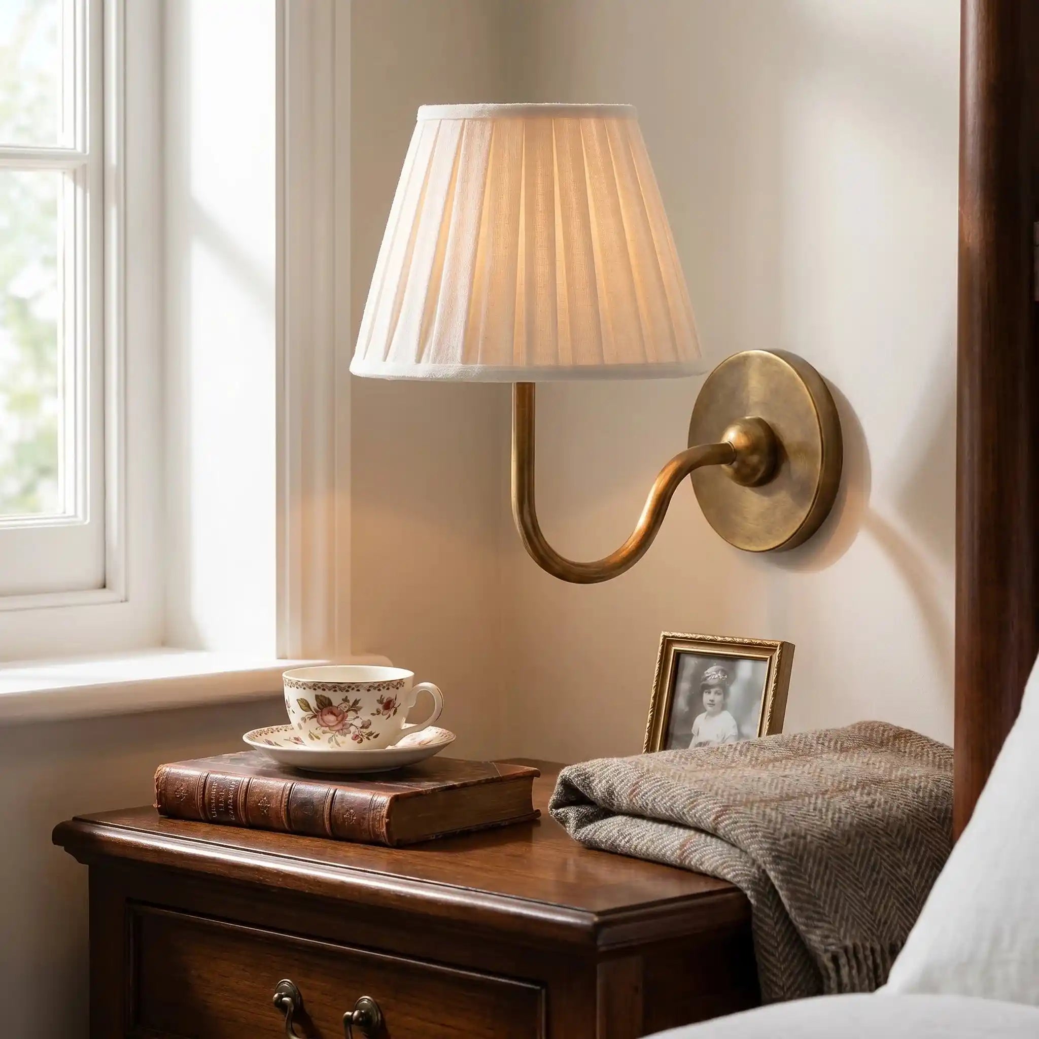 Napkin holder on a wall next to a window with a cup and saucer on a wooden surface.