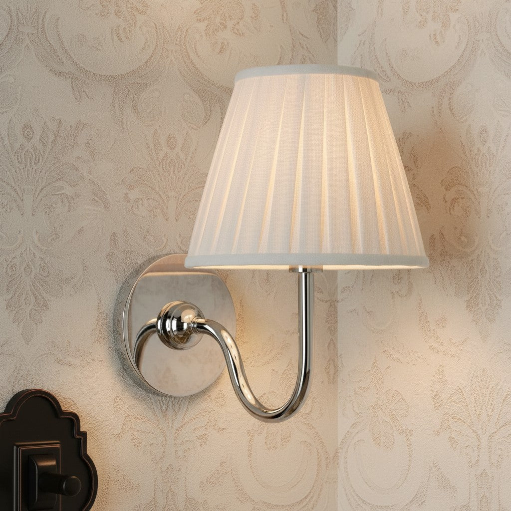 Wall-mounted lamp with pleated white shade against decorative wallpaper