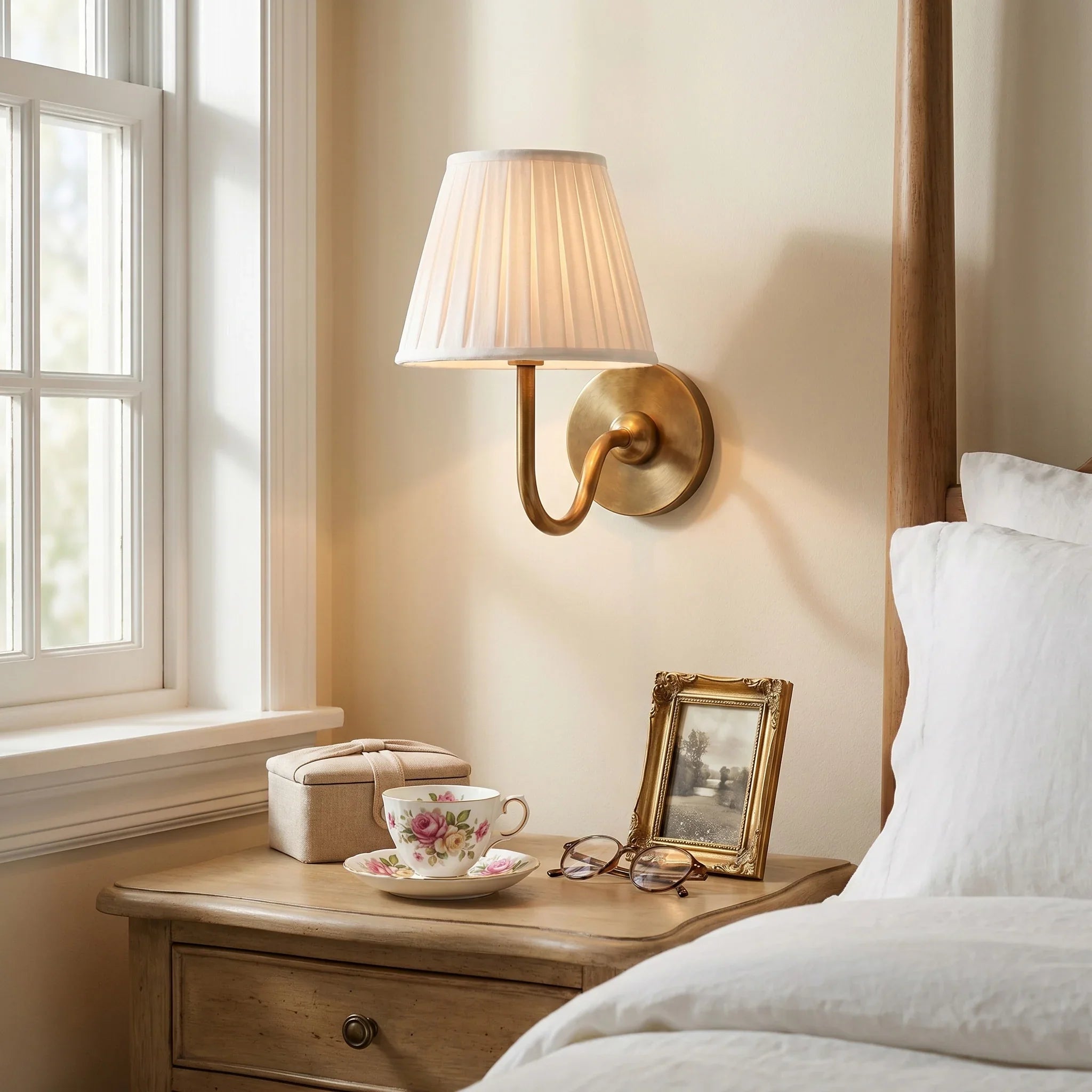 Napkin holder, teacup with saucer, and framed photo on a wooden nightstand next to a bed.