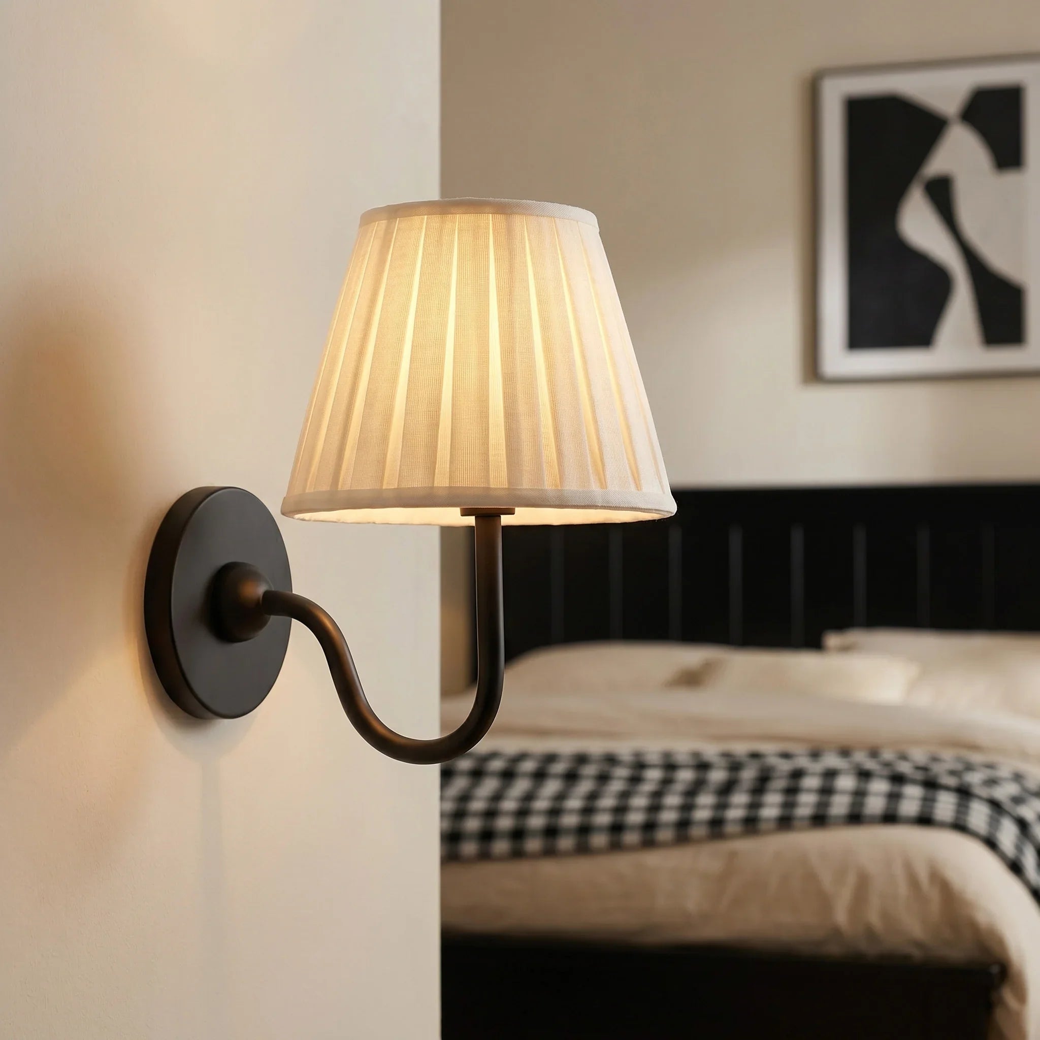 Wall-mounted lamp with pleated shade in a bedroom setting