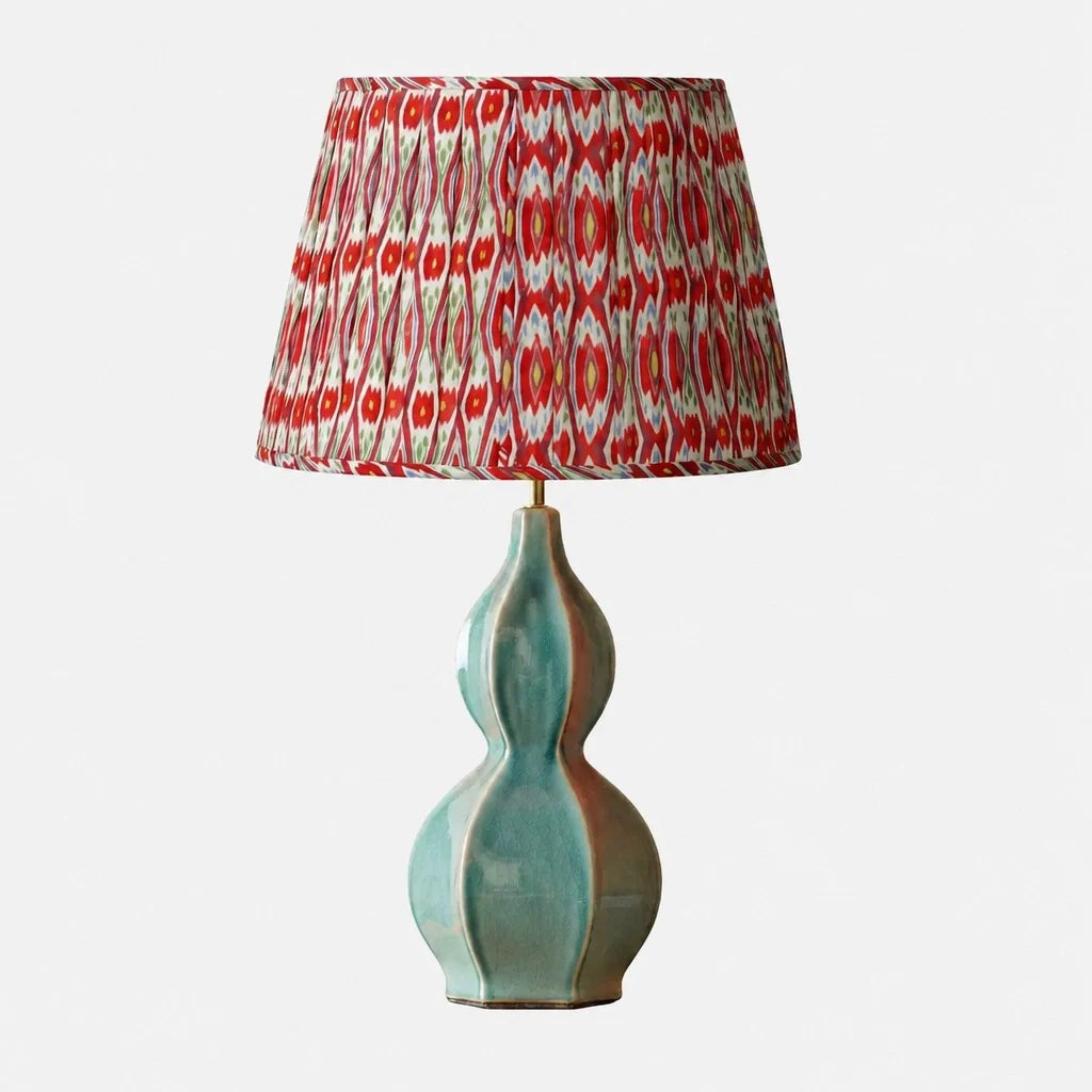Lamp with a decorative red and white patterned shade on a light gray background