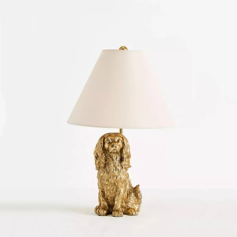 Gold dog-shaped table lamp with a white shade on a light gray background