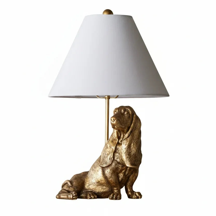 Gold dog-shaped table lamp with a white lampshade on a white background