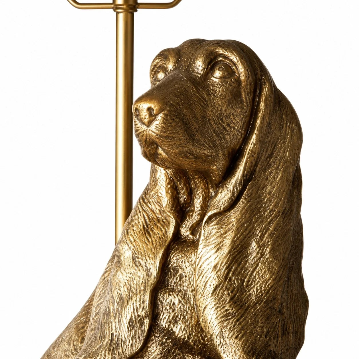 A close-up of a metallic gold dog figurine or lamp base, showing a long-eared dog profile with a polished brass-like finish against a plain white background.