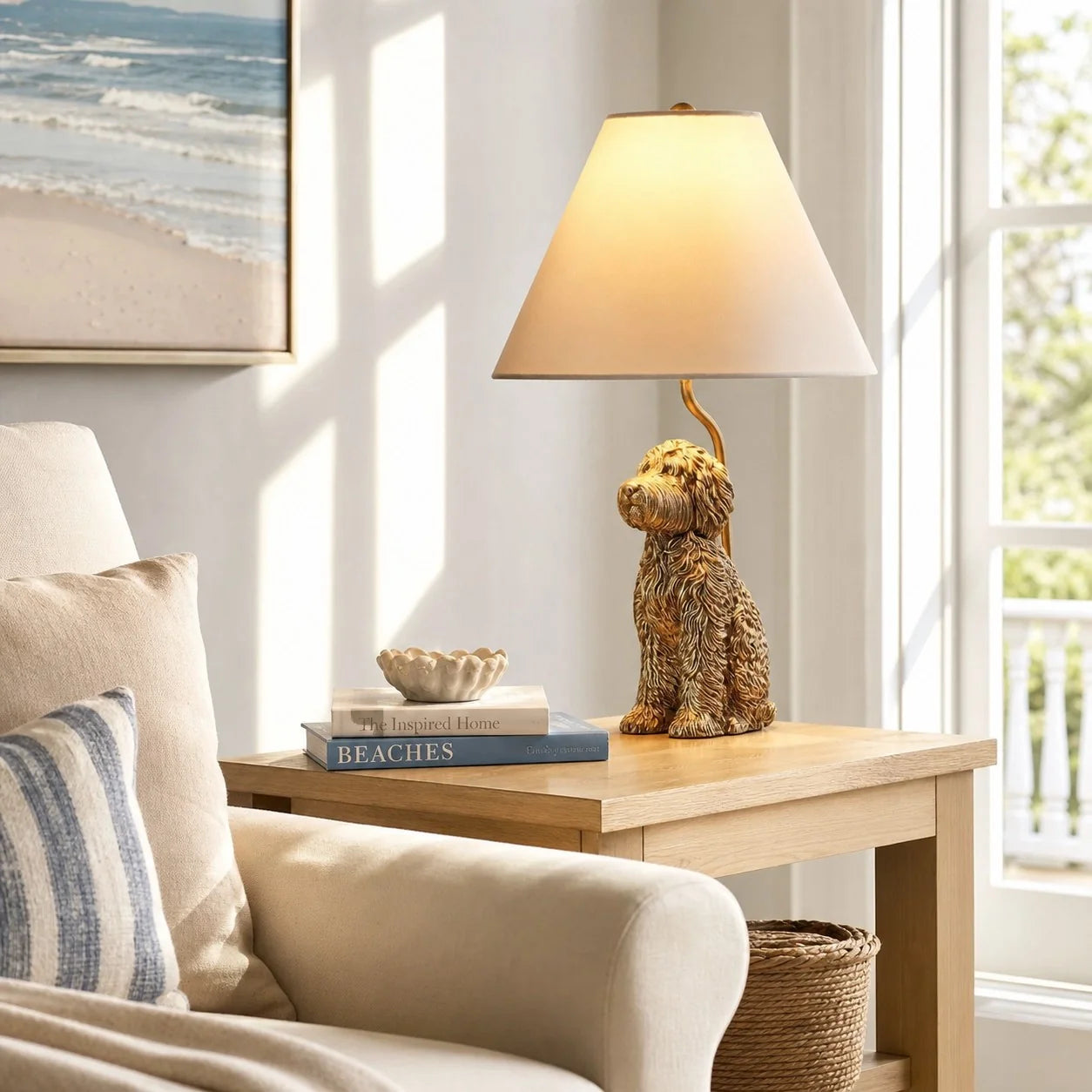 A table lamp with a dog-shaped metallic gold base and a beige conical shade, placed on a light wood side table in a sunlit living room next to a beige armchair.