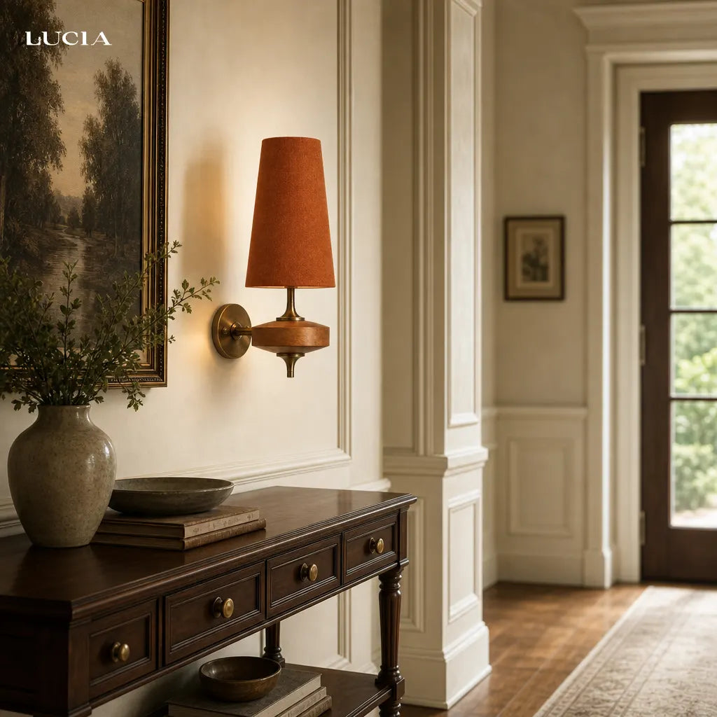 Decorative wall sconce with a warm brown lampshade in a room with a painting and a vase.
