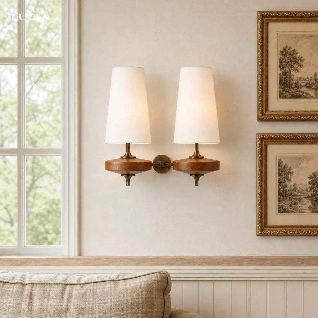 Pair of wall sconces on a wall with framed artwork in a room.