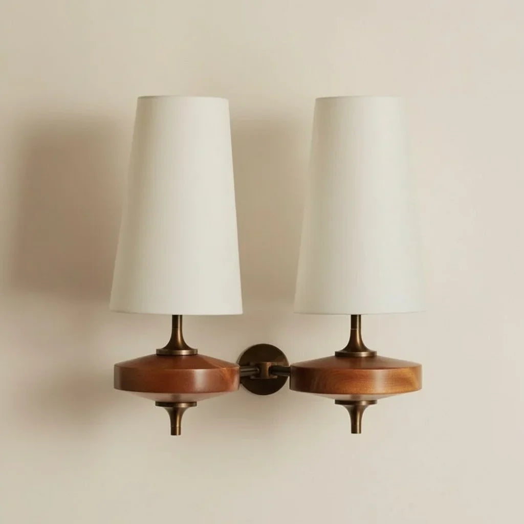 Pair of wall sconces with wooden bases and white lampshades on a beige wall.